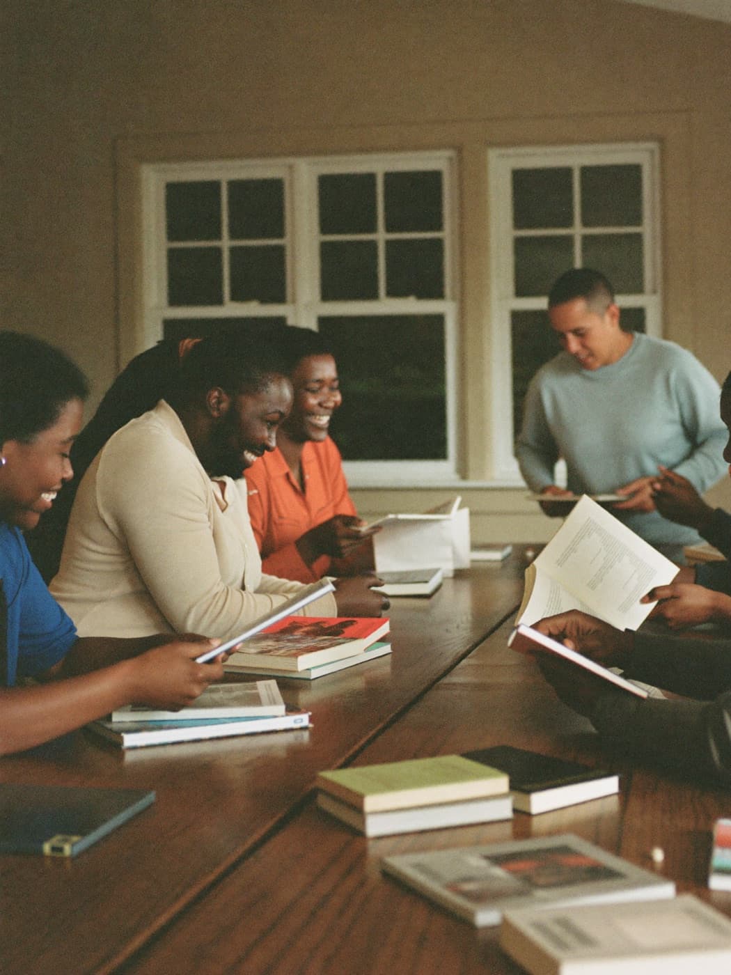 Volunteers sorting donated books at a long wooden table, laughing mid-conversation